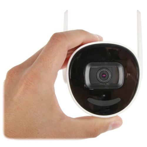 Na zdjęciu widoczna jest biała kamera monitoringu z dwoma antenami, trzymana w dłoni. Kamera ma czarny panel przedni z widocznym obiektywem pośrodku.