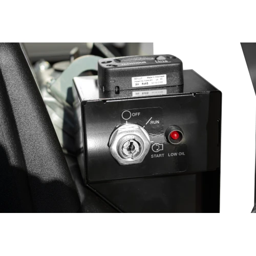 Zbliżenie na panel sterowania agregatu prądotwórczego z widocznym kluczykiem w stacyjce oraz przyciskiem startu. Obok znajduje się wskaźnik niskiego poziomu oleju i przełącznik trybu pracy.