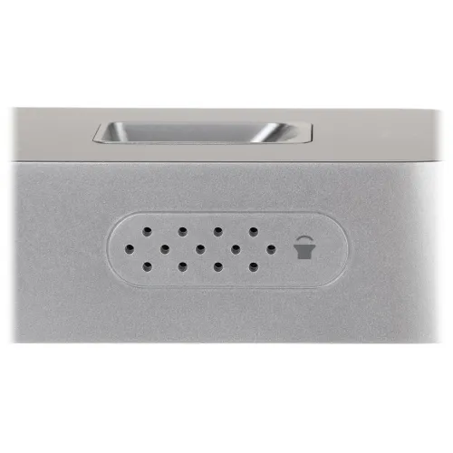 Zbliżenie na srebrny głośnik z widocznymi otworami wentylacyjnymi i ikoną głośnika. Obudowa ma prostokątny kształt z zaokrąglonymi krawędziami.