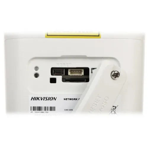Zdjęcie przedstawia zbliżenie na panel tylni urządzenia sieciowego Hikvision, z widocznym gniazdem na kartę pamięci oraz przyciskiem reset. Na panelu znajduje się również etykieta z nazwą producenta i specyfikacjami technicznymi.