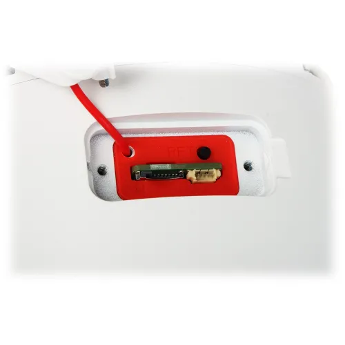 Zdjęcie przedstawia zbliżenie na gniazdo karty pamięci oraz przycisk reset na białym urządzeniu. Widać czerwony panel z otworem na kartę i czarnym przyciskiem.