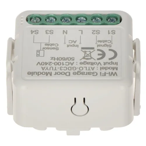 Zdjęcie przedstawia biały moduł elektroniczny z kilkoma zielonymi złączami na górze oraz oznaczeniami technicznymi na powierzchni. Moduł posiada przycisk resetu i jest przeznaczony do sterowania drzwiami garażowymi.
