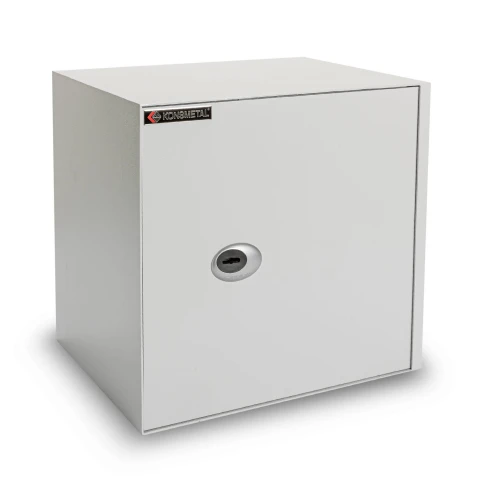 Na zdjęciu znajduje się biały sejf o prostokątnym kształcie z zamkiem na klucz umieszczonym centralnie na drzwiach. W lewym górnym rogu widoczna jest nazwa producenta na czarnym tle.