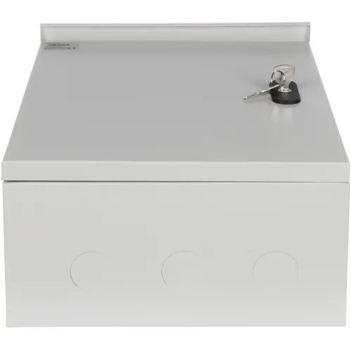 Metalowa skrzynka elektryczna w kolorze szarym z zamkiem na klucz na górze. Widoczne są trzy okrągłe otwory na przedniej ściance.