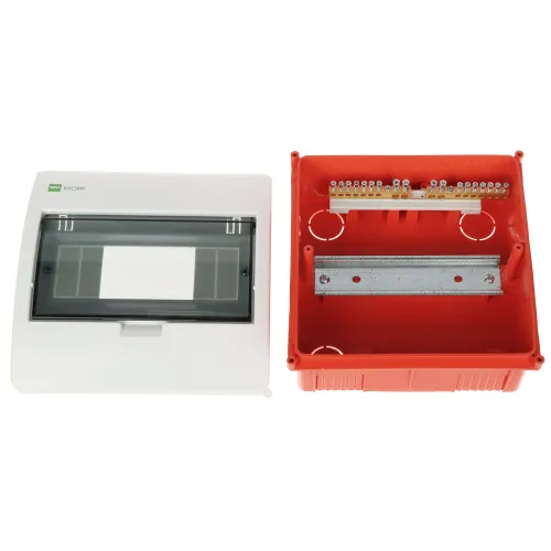 Na zdjęciu znajduje się otwarta obudowa elektryczna z białą pokrywą i przezroczystym panelem, obok czerwonej podstawy z metalową szyną montażową i listwą zaciskową. Obudowa jest przeznaczona do instalacji elektrycznych, umożliwiając montaż i organizację komponentów.