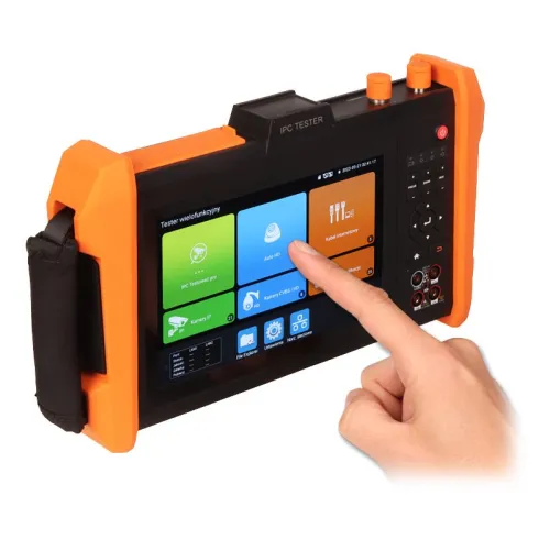 Osoba obsługuje wielofunkcyjny tester CCTV z dużym ekranem dotykowym i pomarańczowymi uchwytami ochronnymi. Na ekranie widoczne są różne ikony aplikacji i funkcji testera.